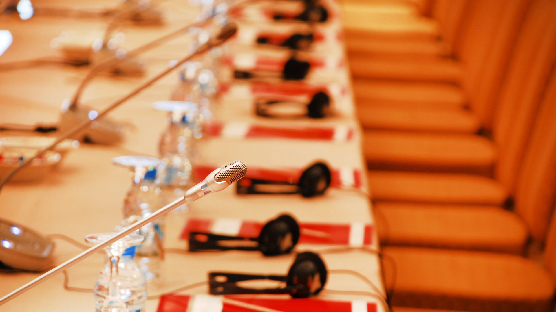Fotografía de hilera de butacas en un salón de actos, en primer plano, el micrófono de una de las sillas utilizado para las intervenciones de los presentes