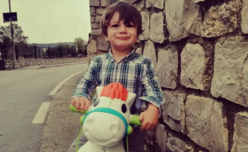 Imagen del pequeño Antonio sonriente sobre un caballito de juguete.