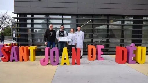 Fotografía frente al hospital en la que los investigadores Àngels García Cazorla y Alfonso De Oyarzábal Sanz reciben el cheque por parte de la Asociación Mi Princesa Rett