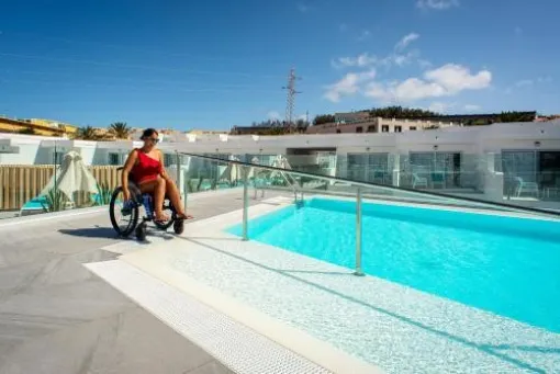 Una persona usuaria de silla ruedas en una piscina con una rampa de acceso