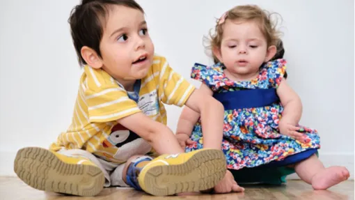Fotografía de un niño y una niña sentados en el suelo